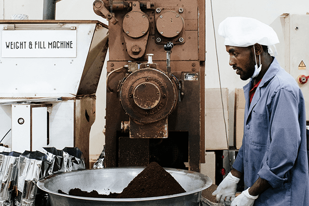 Mitarbeiter steht an einer professionellen Kaffeemühle